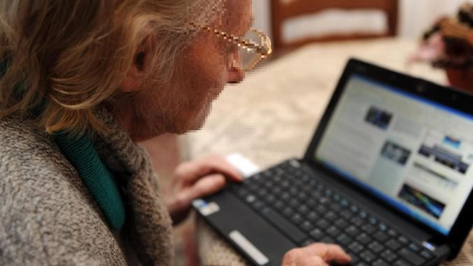 Un'anziana utilizza un computer portatile (foto Ansa)
