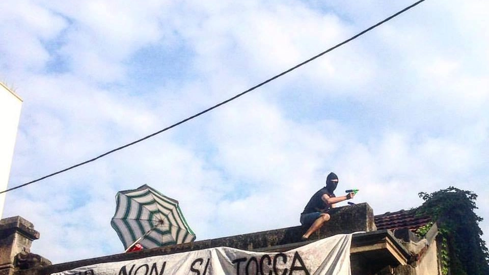 Un manifestante sul tetto dell'ex asilo occupato