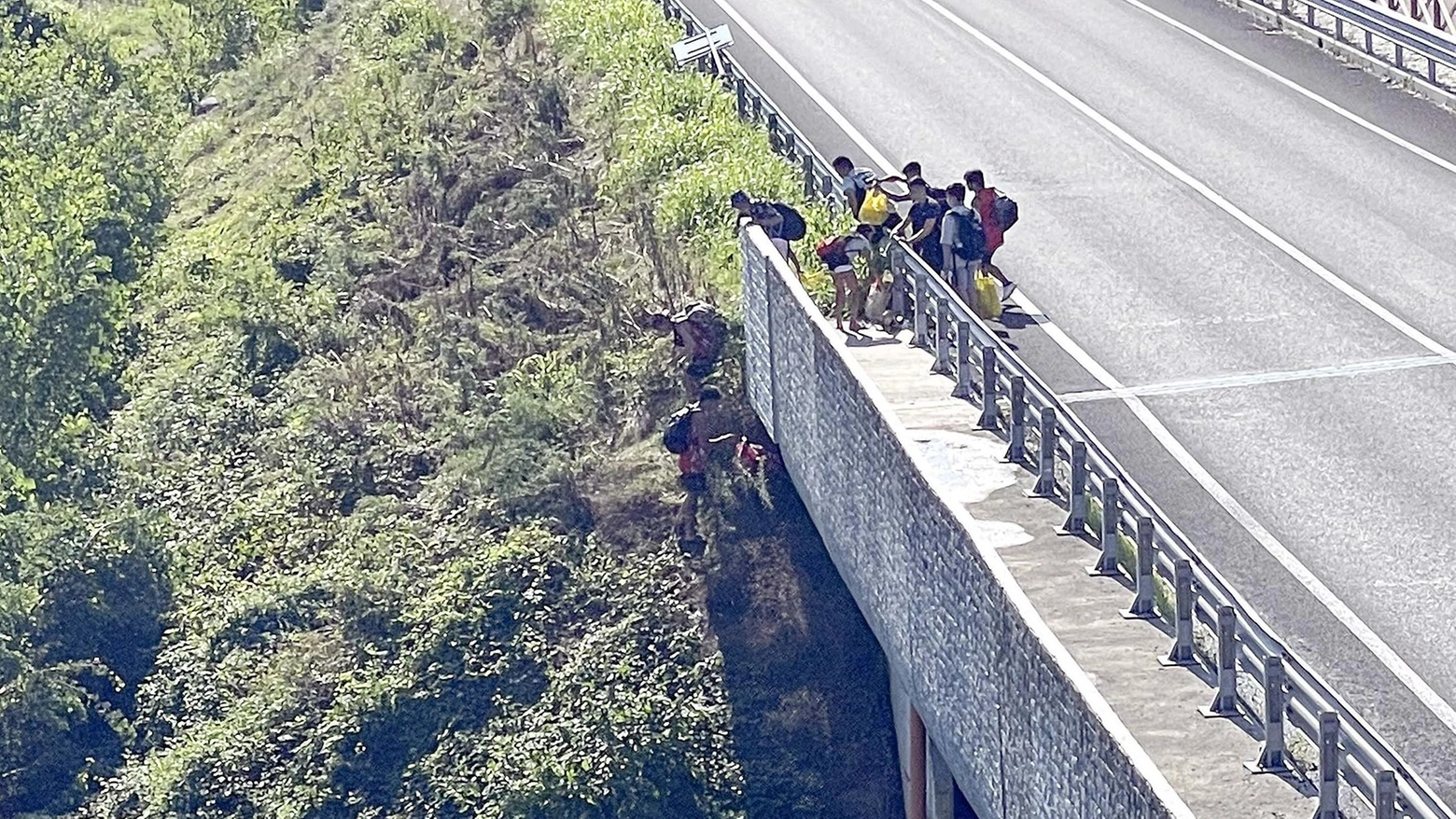 Un gruppo di ragazzi cerca un accesso al fiume camminando accanto alla tangenziale Un gruppo di ragazzi cerca un accesso al fiume camminando accanto alla tangenziale