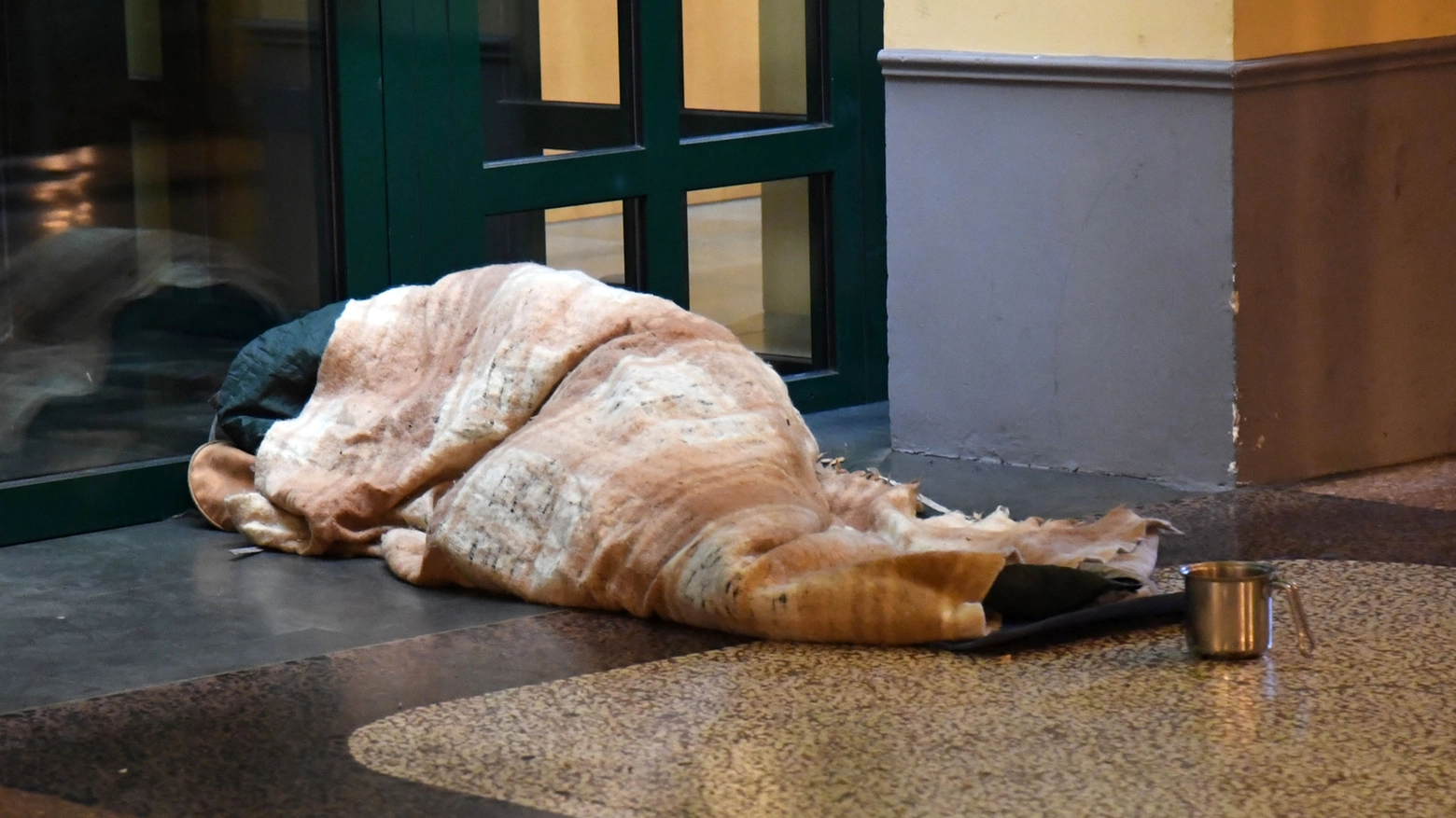 Un senzatetto dorme sotto i portici (Archivio)