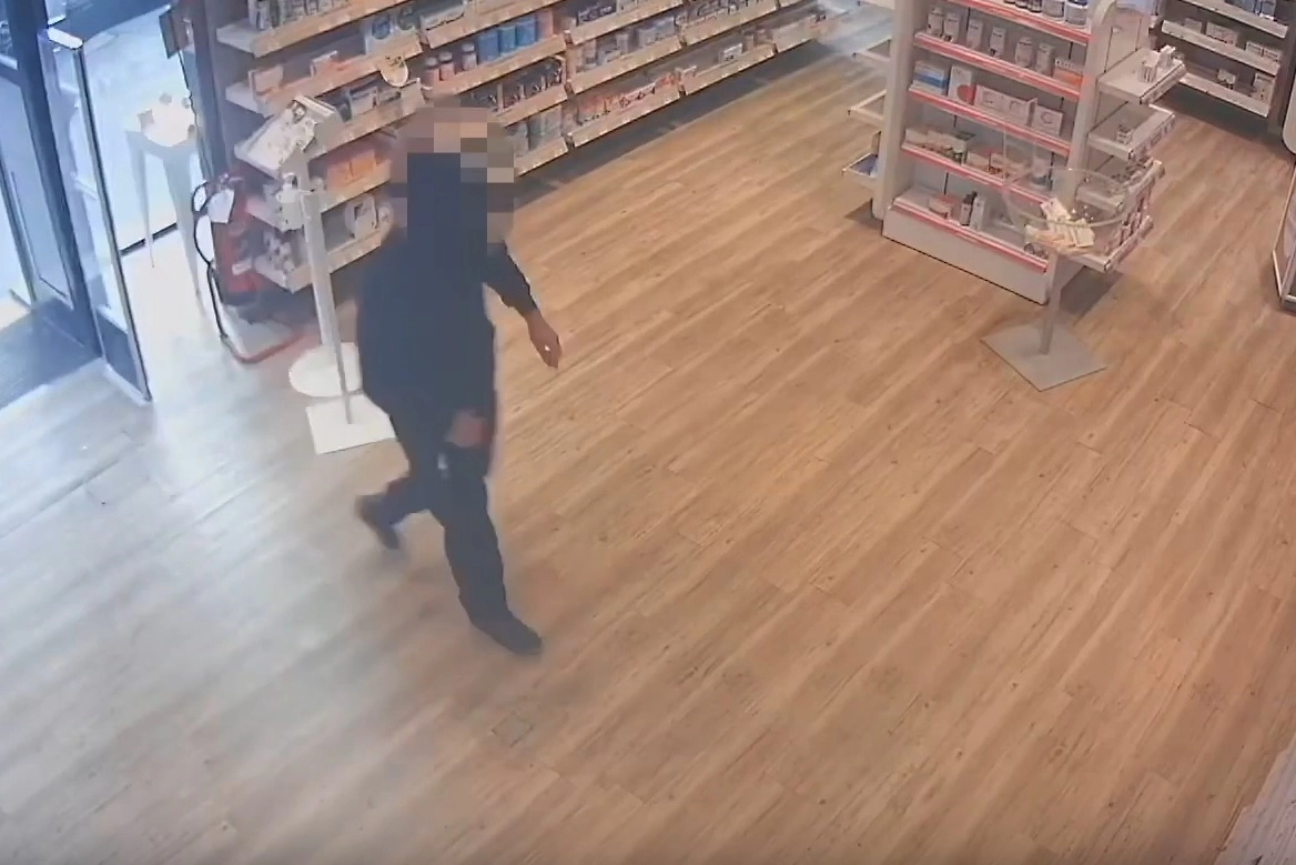 Il rapinatore in azione nella farmacia di via Ronchi
