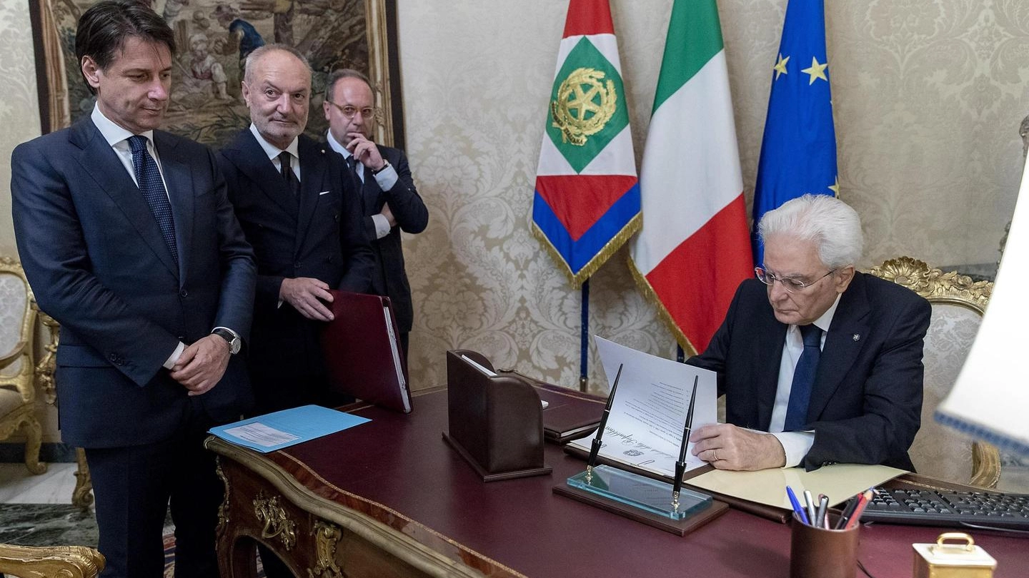 Mattarella e Conte durante la firma dei decreti di accettazione dell'incarico (Ansa)