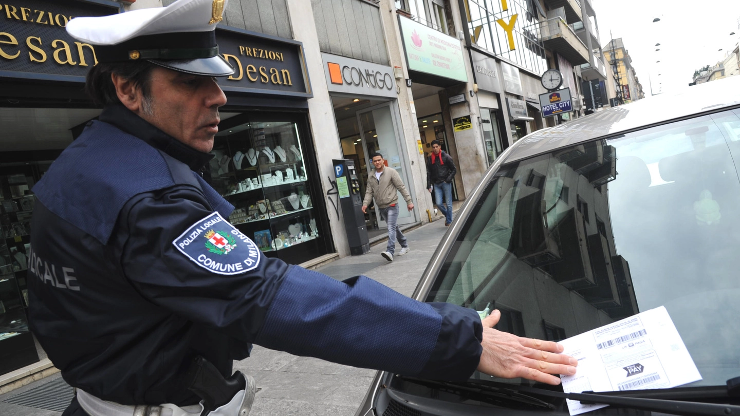 Un agente della Polizia locale multa un’auto in sosta vietata