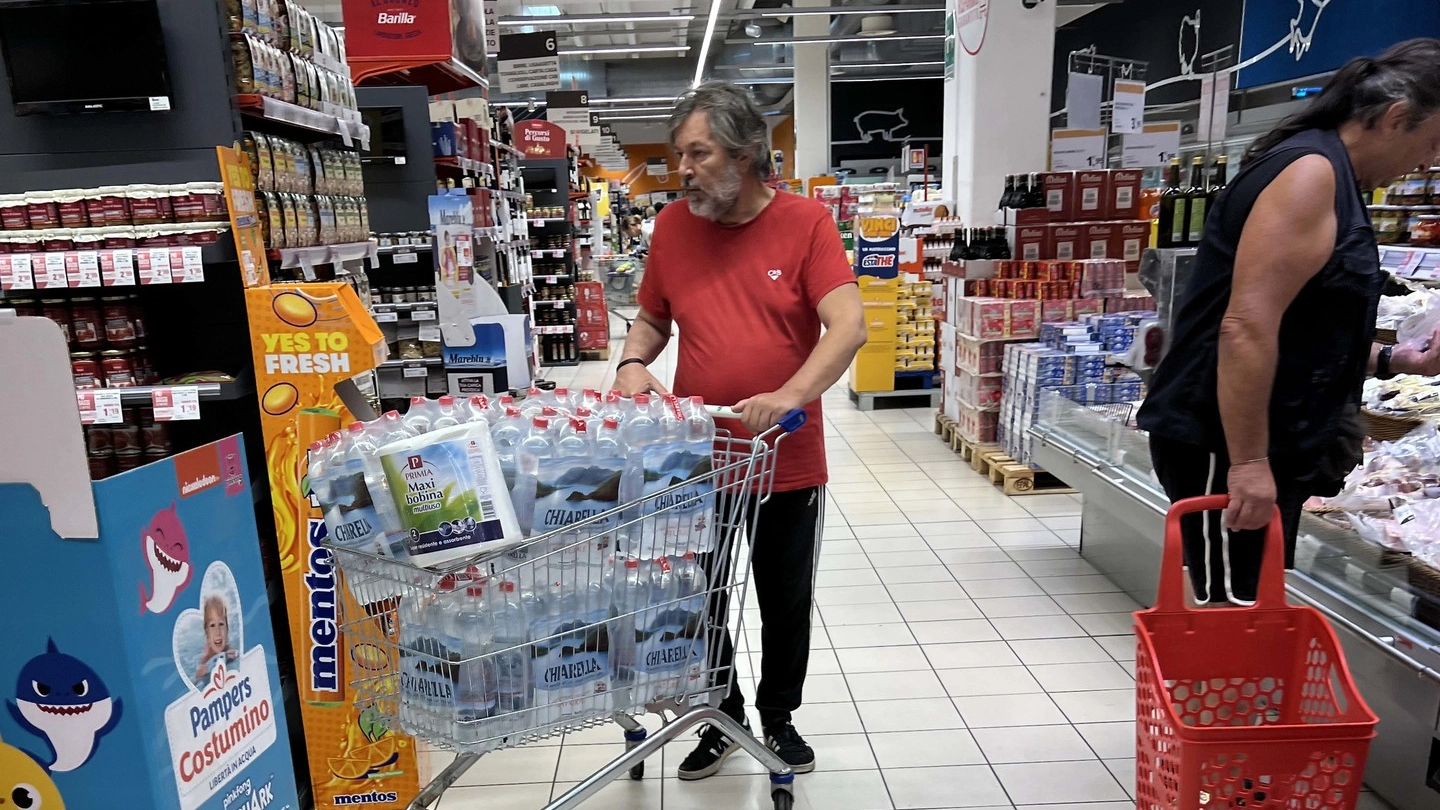 la gente fa scorte di acqua al supermercato