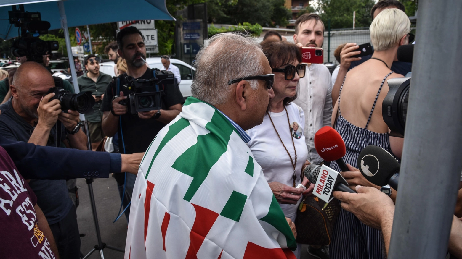 Andrea, imprenditore milanese avvolto nella bandiera di Forza Italia davanti al San Raffaele