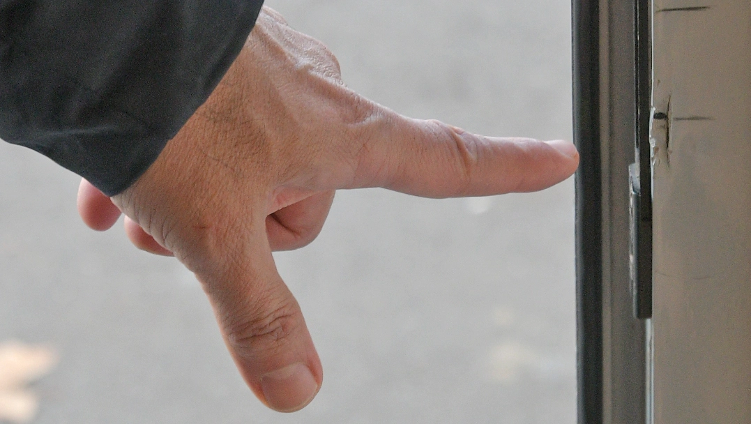 Il titolare del negozio derubato indica il punto in cui la porta d'ingresso è stata forzata dai ladri