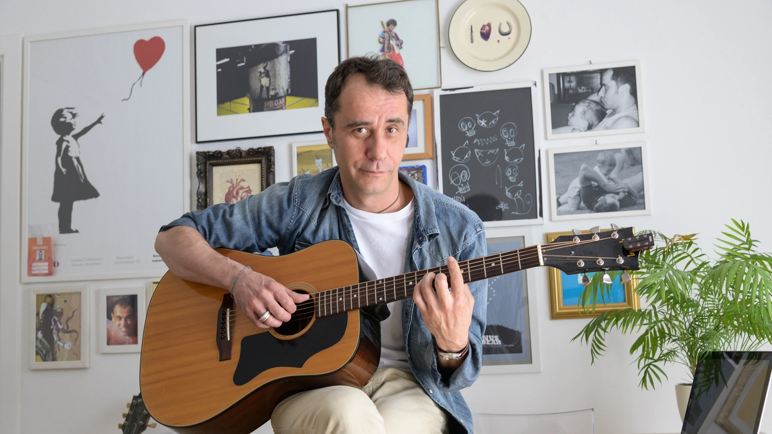 Massimiliano Pelan nella sua casa con chitarra e pc strumenti di lavoro (NewPress)