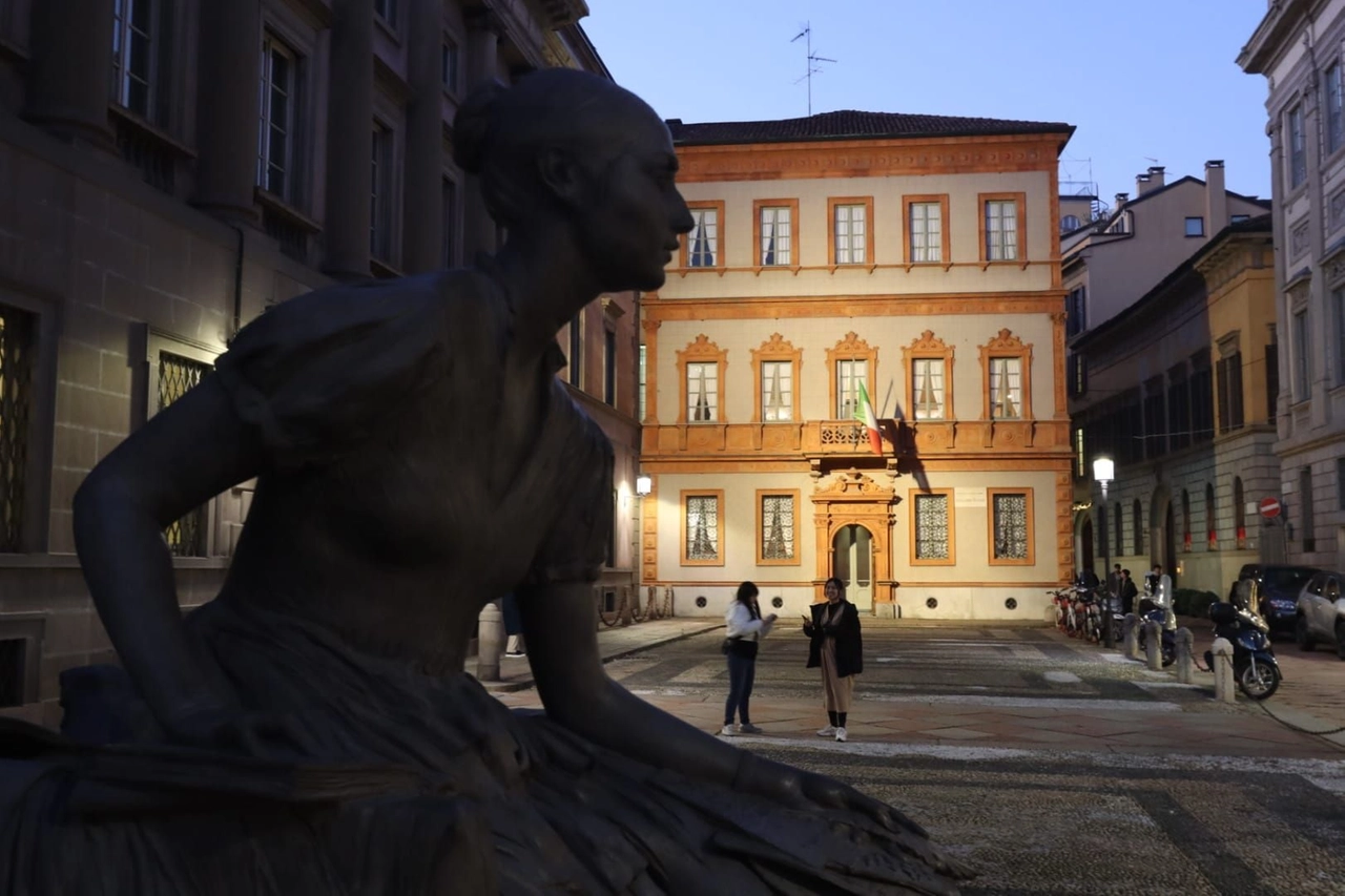 La facciata illuminata di Casa Manzoni, dietro la statua di Cristina di Belgiojoso