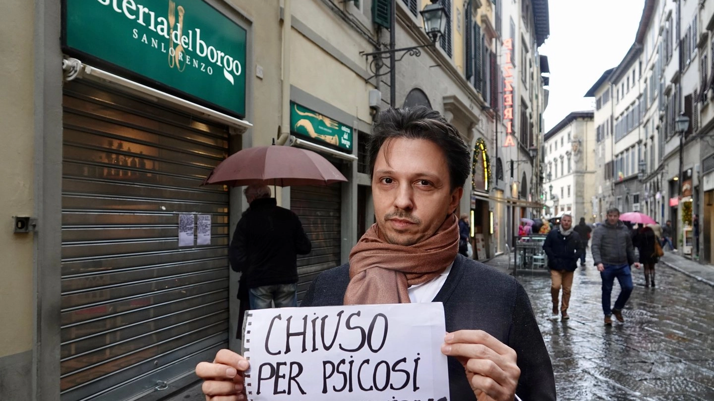 Un ristoratore mostra il cartello "chiuso per psicosi" (foto New Press Photo)