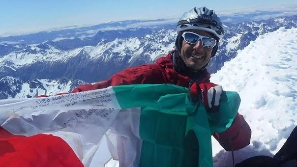 Luca Colli in cima a una vetta alpina col tricolore