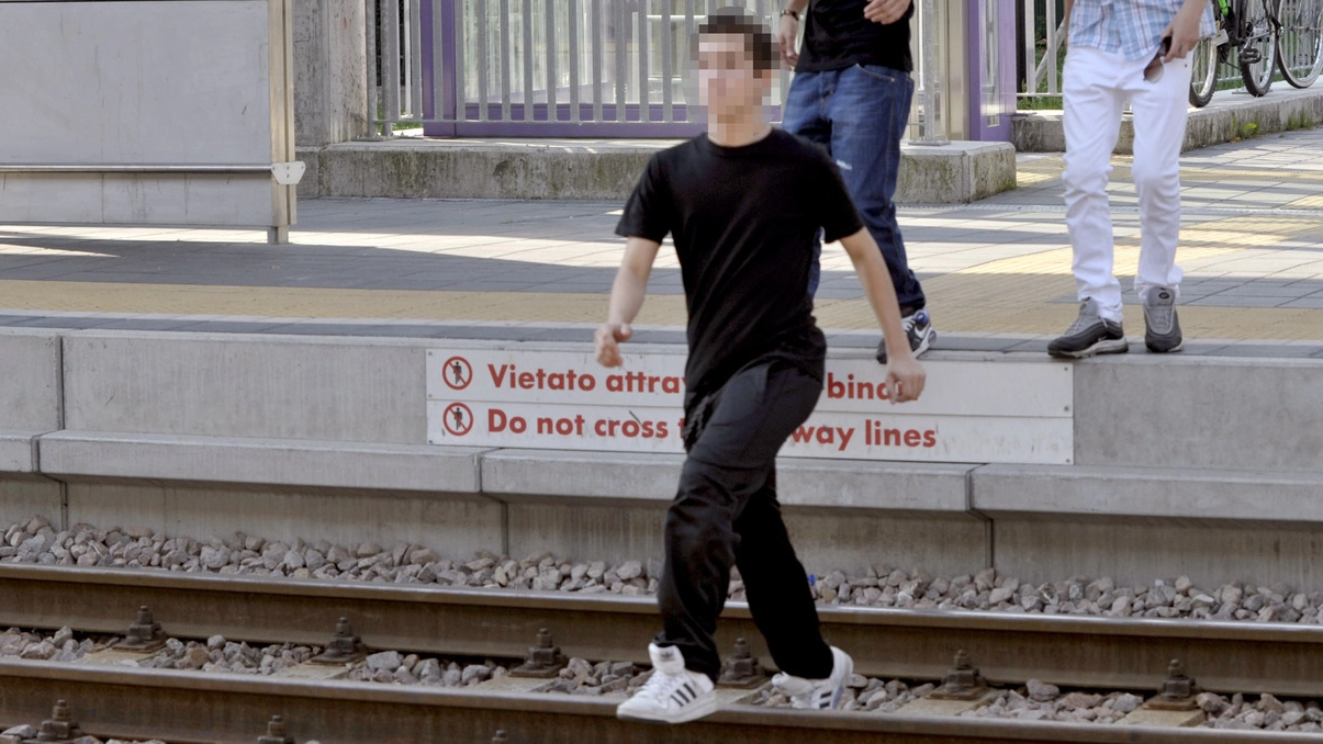 Un giovane attraversa i binari in stazione a Trezzano