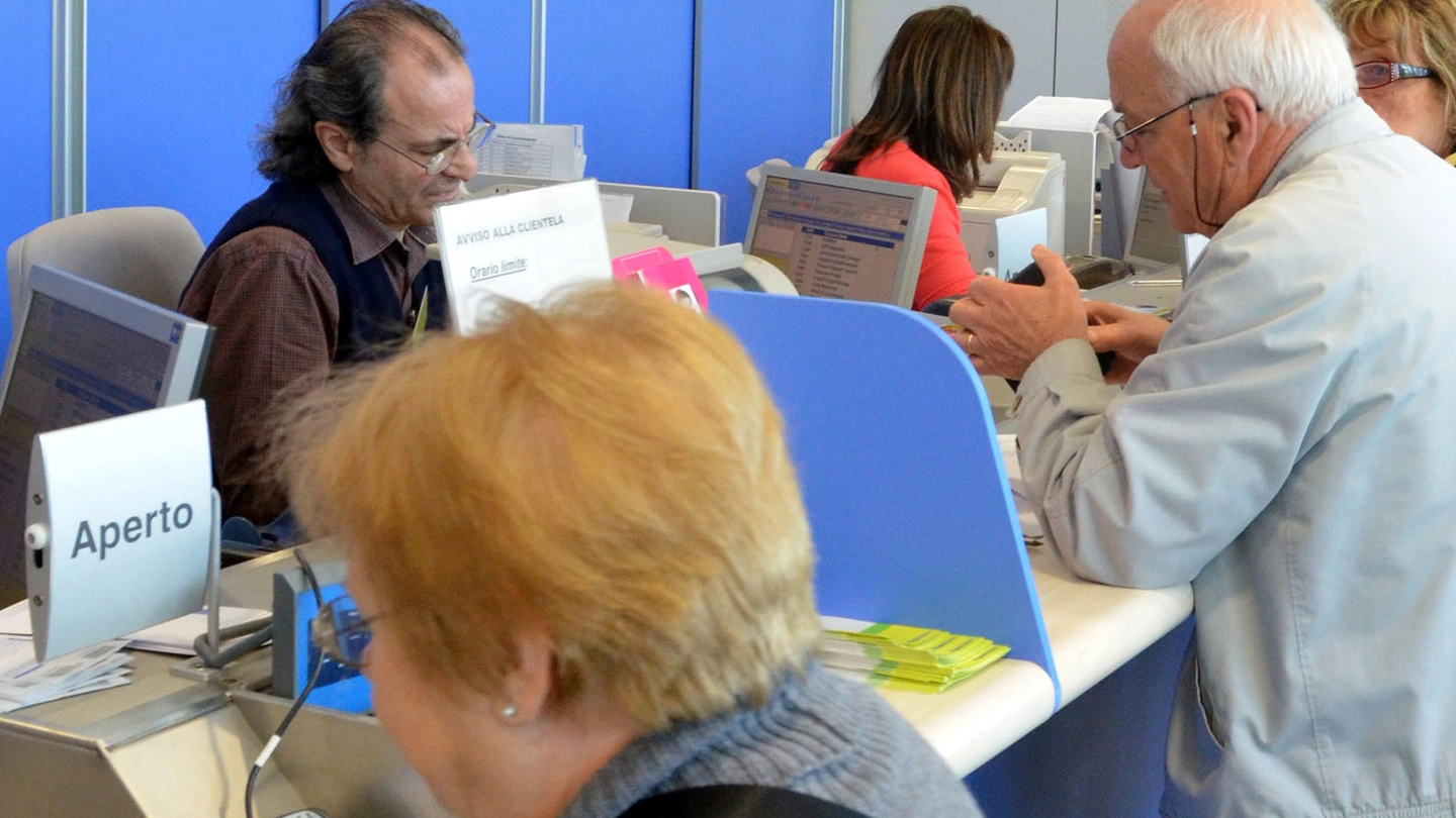 Alcuni pensionati mentre agli sportelli ritirano la pensione in un ufficio postale