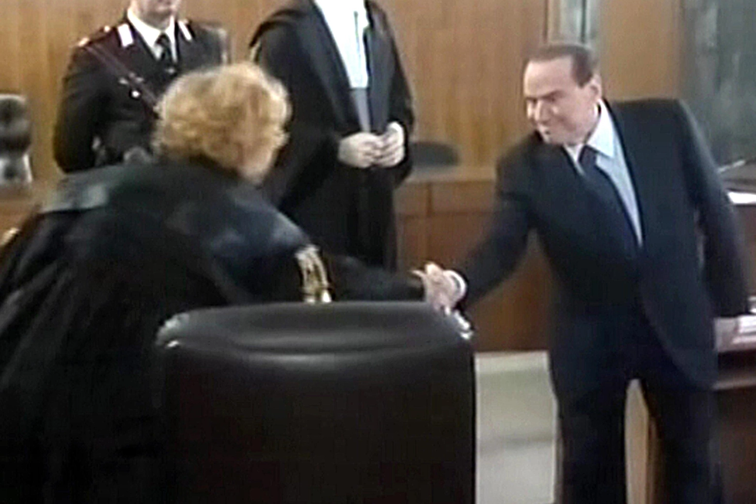 La storica stretta di mano e il sorriso forzato di Silvio Berlusconi