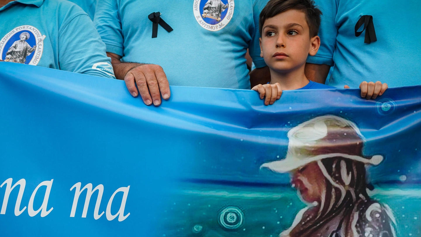 Un bambino tiene lo striscione con l’immagine di Giulia nella fiaccolata in suo onore