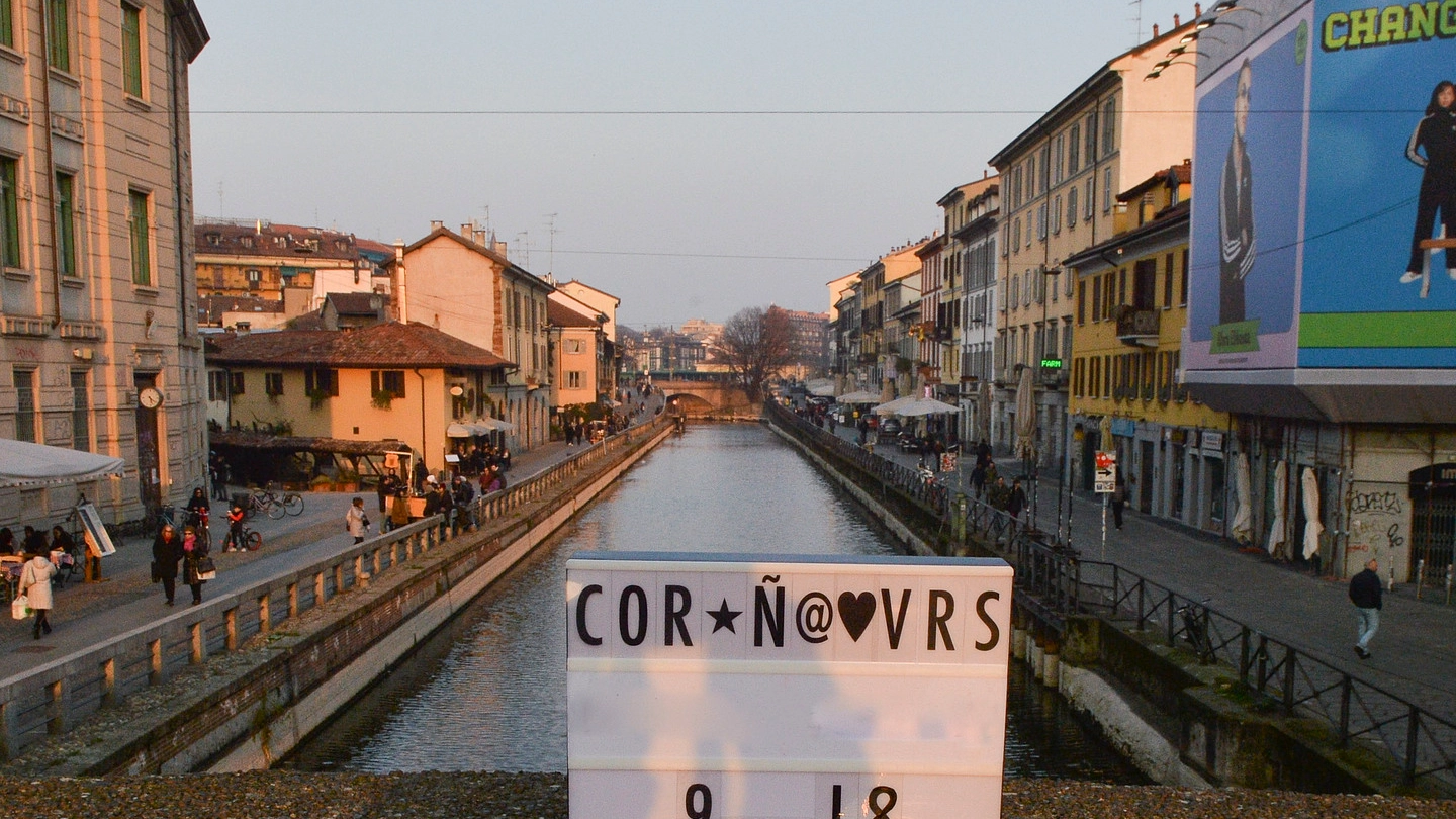Un cartello ironico sul virus appoggiato su un ponte del Navigli