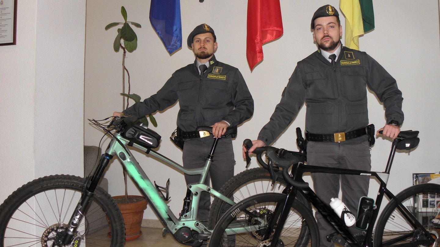 Due finanzieri delle Fiamme Gialle di Tirano con le bici di contrabbando sequestrate