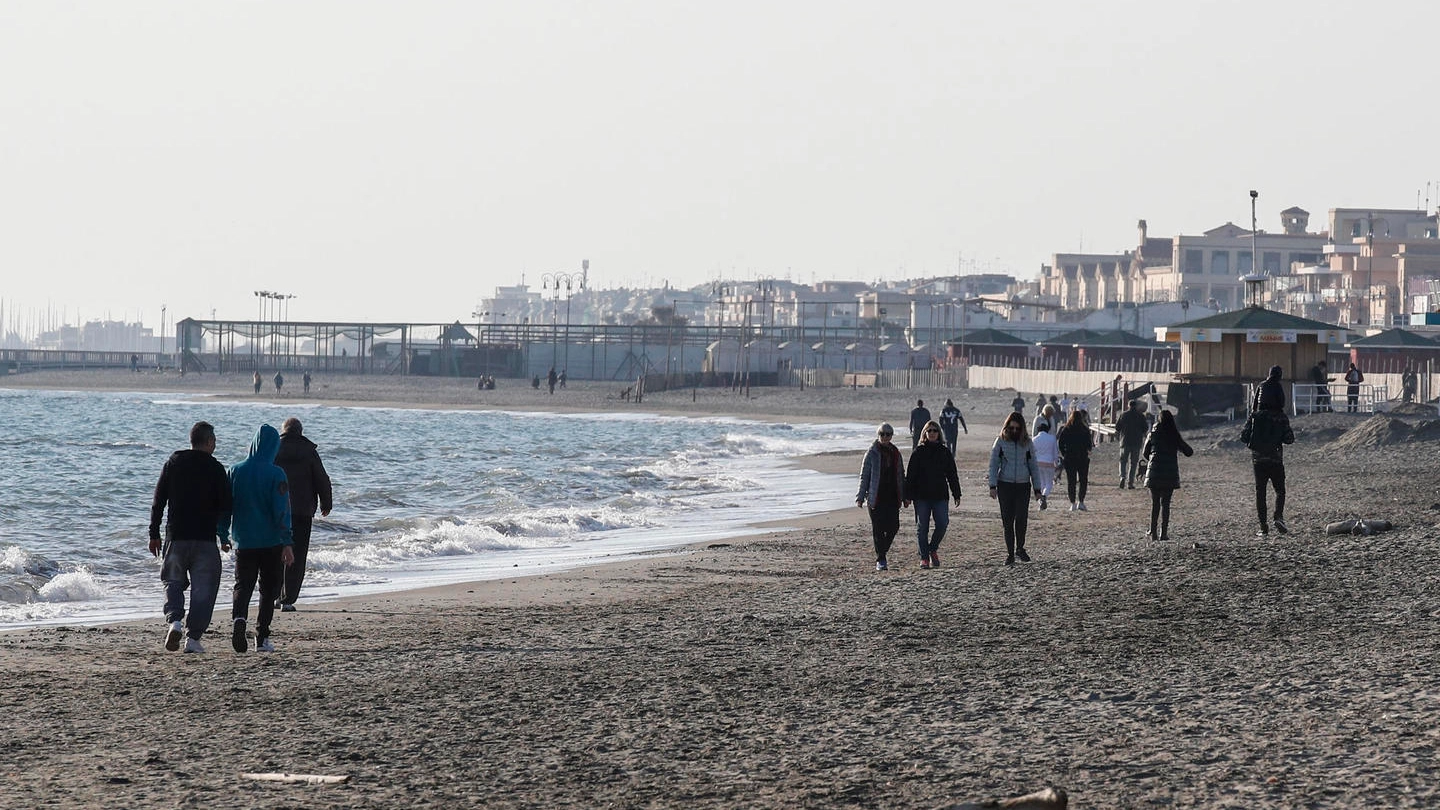 Coronavirus, persone camminano in spiaggia a Ostia (Ansa)