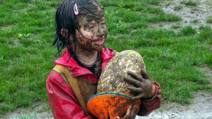 Una piccola atleta della scuola rugby sul terreno reso impraticabile dalla pioggia