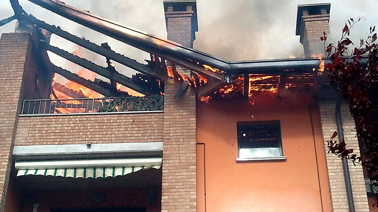 Le fiamme all’altezza del tetto; a sinistra, uno dei pompieri impegnati nell’intervento