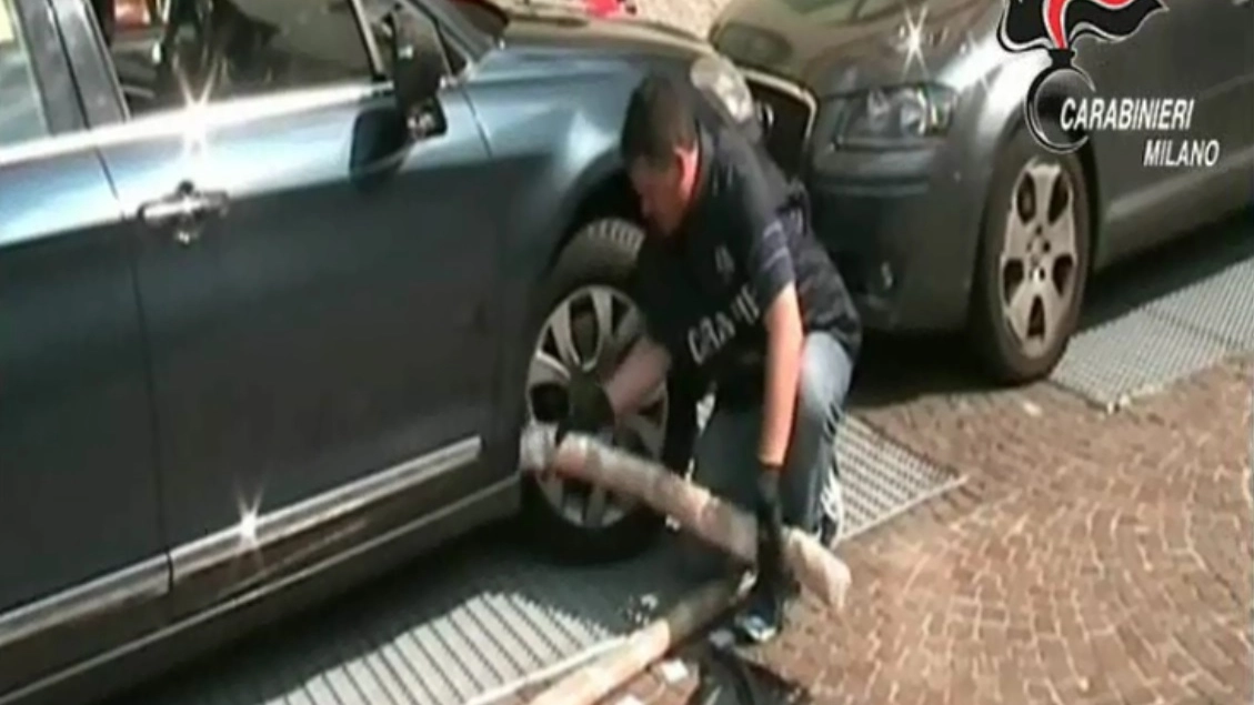 Un carabiniere estrae panetti di droga dall'intercapedine di una portiera d'auto