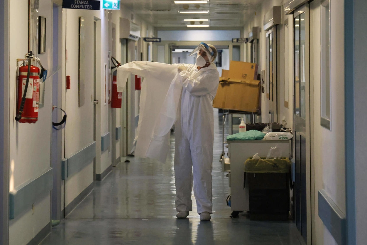Un operatore sanitario indossa le protezioni anti Covid (Ansa)
