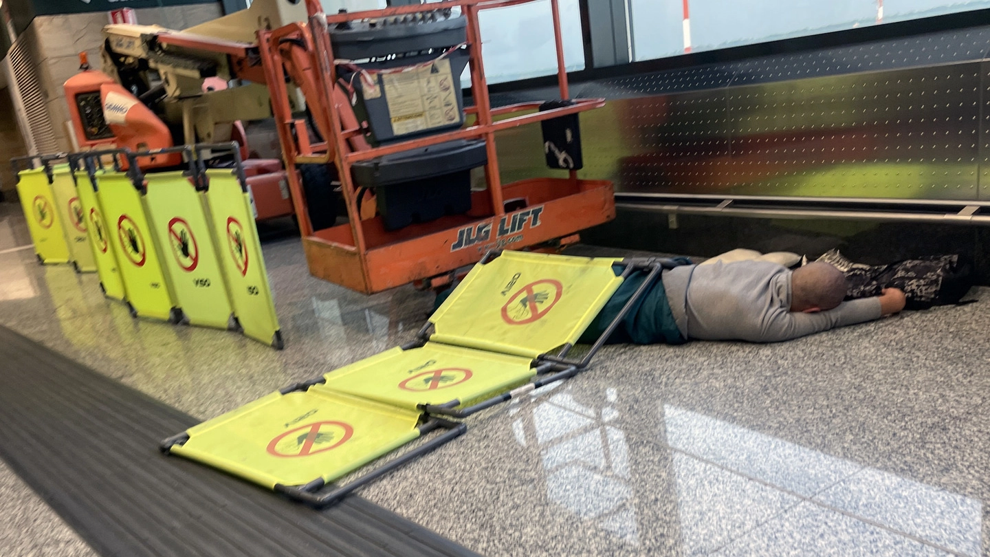 Un senzatetto che dorme all'interno dell'aeroporto di Malpensa