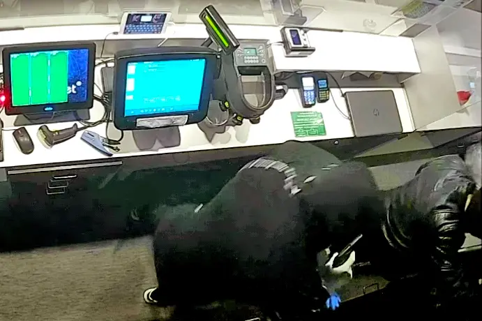Uno dei rapinatori minaccia con la pistola un dipendente della sala slot
