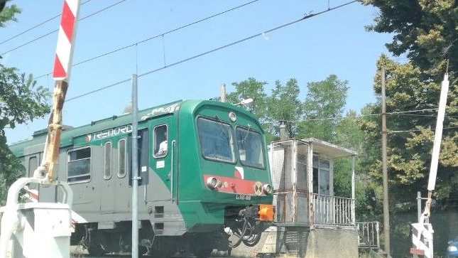 Un treno al passaggio a livello (Foto archivio)