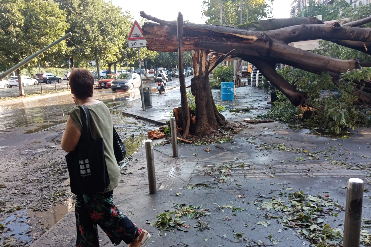 Una passante osserva incredula i danni della tempesta notturna