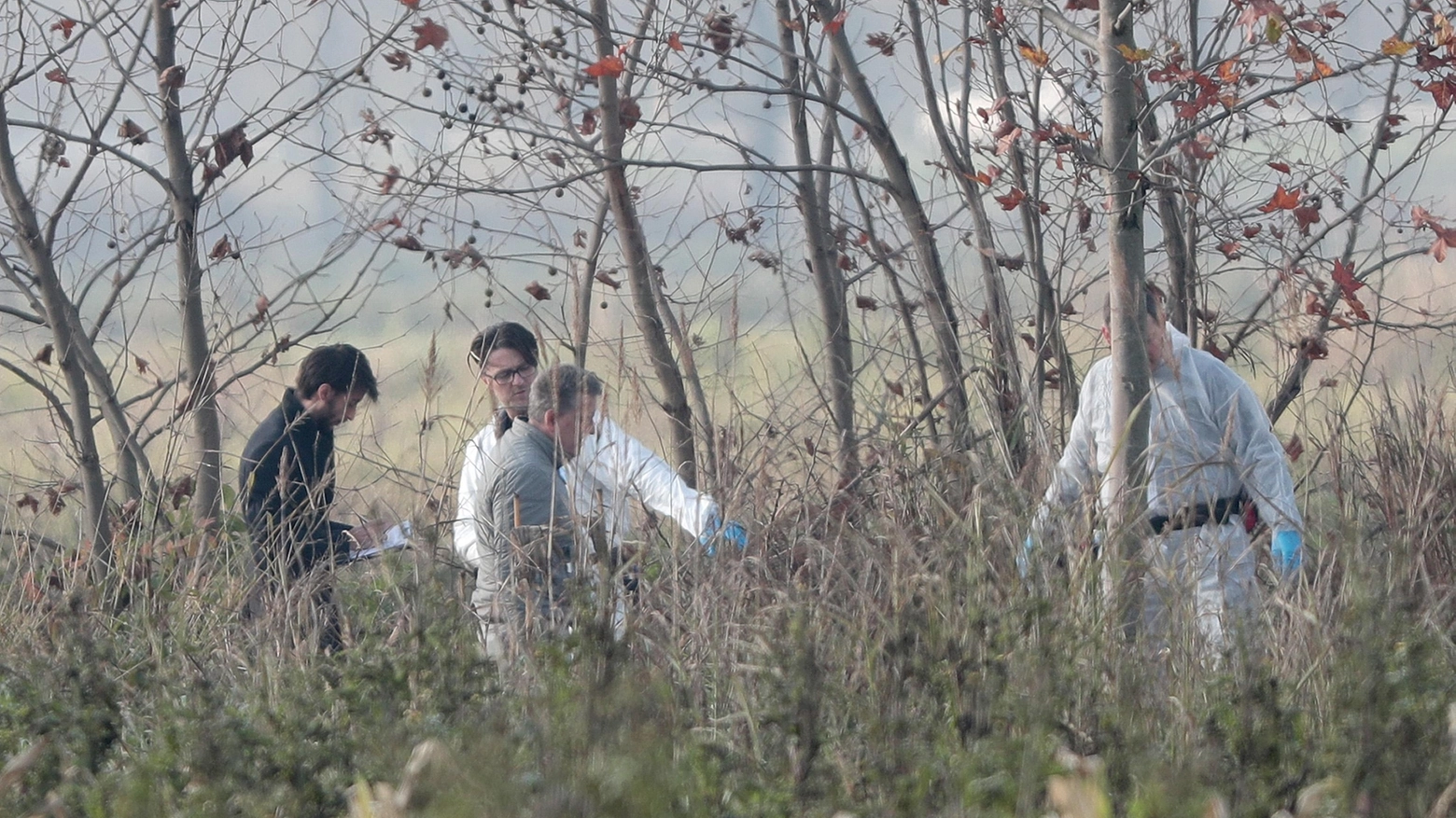 Agenti della Polizia Scientifica effettuano rilievi in una zona nelle campagne di Azzano