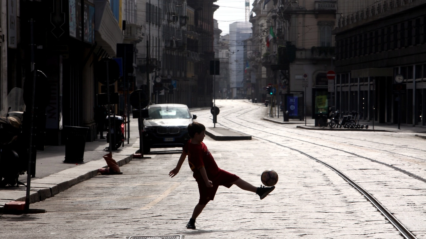 Un bambino gioca a palla in una strada deserta