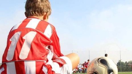 Un baby calciatore seduto accanto a un pallone