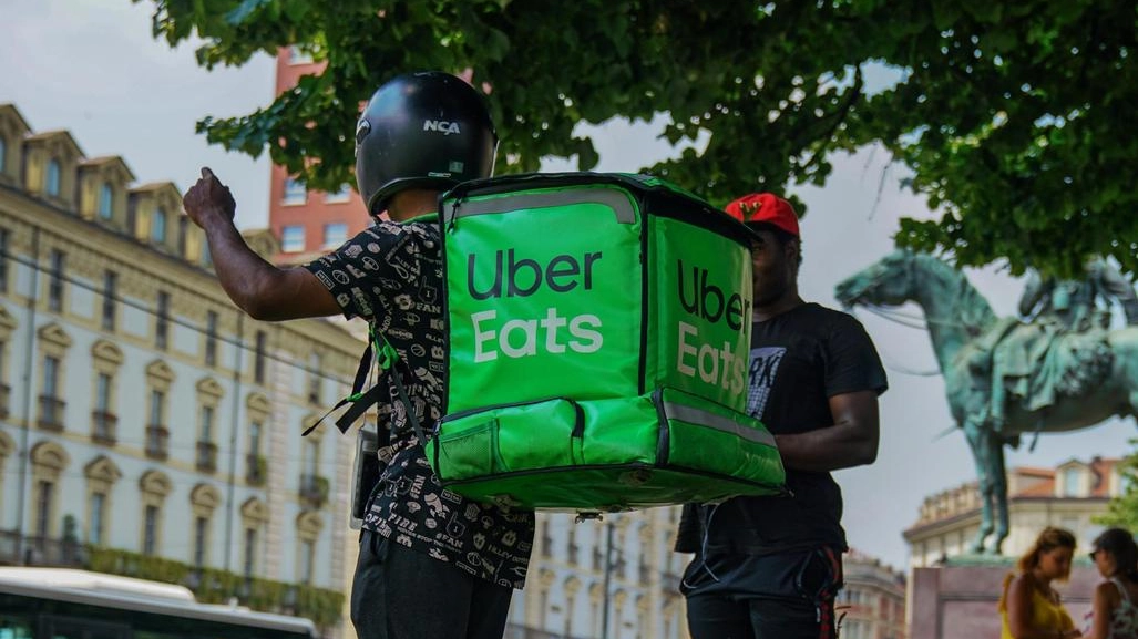 Due riders di Uber Eats cercano refrigerio all'ombra di un albero per continuare il giro