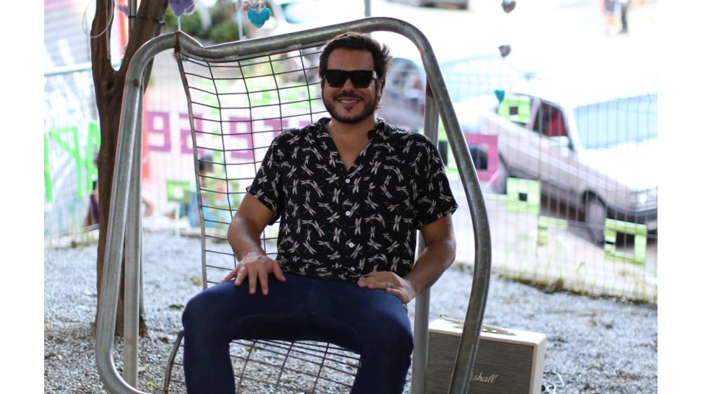 Alê Jordão con la sua iconica sedia in rete metallica riciclata