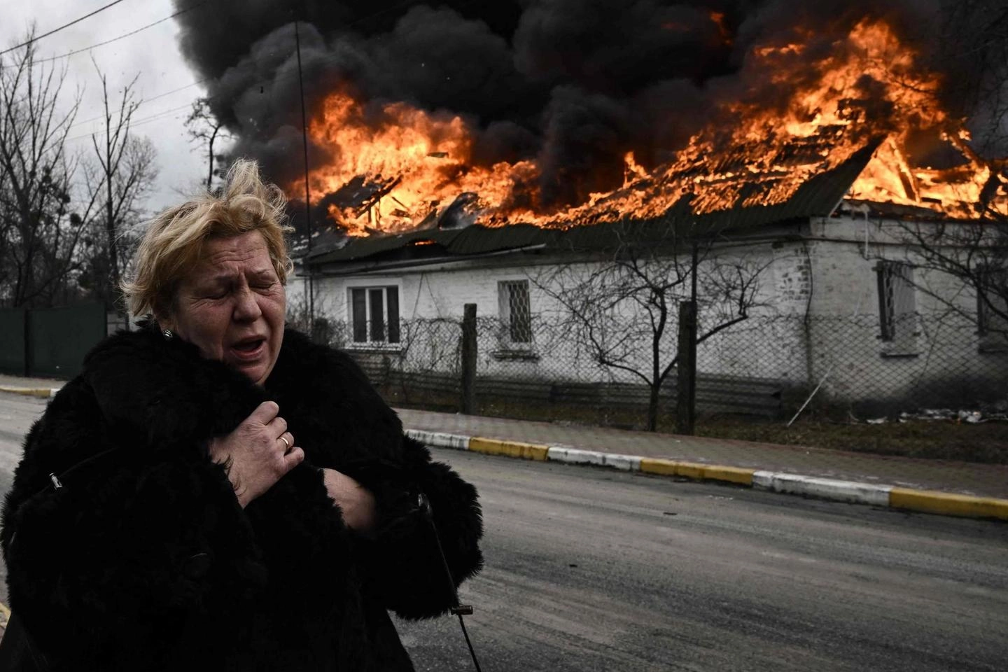 Irpin, il pianto di una donna davanti alla sua casa in fiamme (Ansa)
