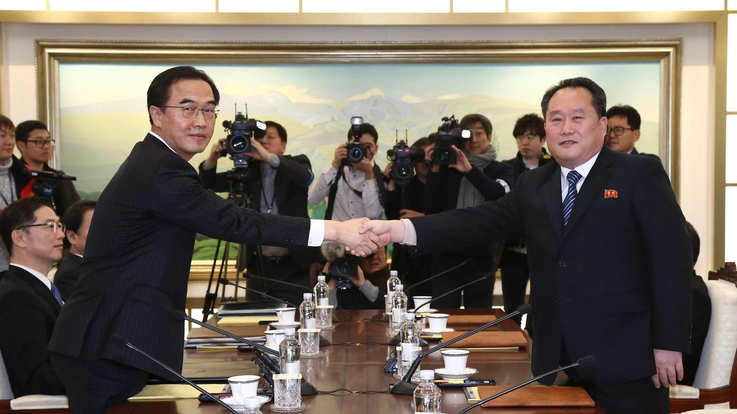 La stretta di mano tra i delegati delle due Coree (Ansa)