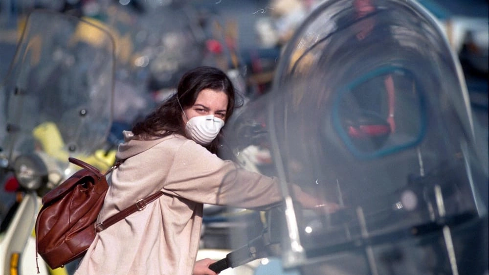 Una ragazza si protegge dall'aria con la mascherina (Foto d'Archivio)