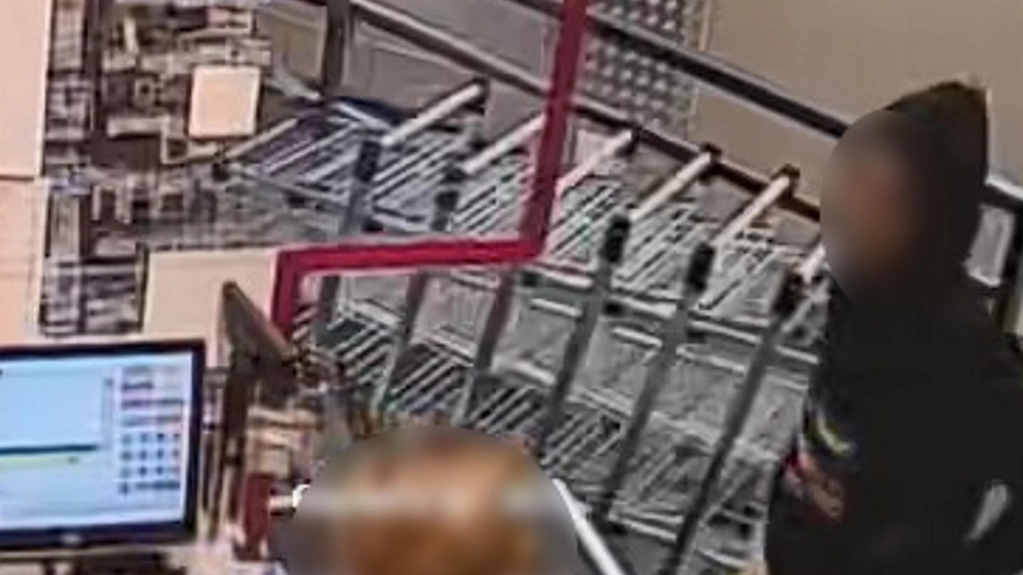 Il rapinatore ripreso da una telecamera del negozio mentre minaccia la cassiera