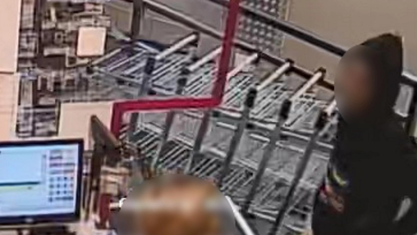 Il rapinatore ripreso da una telecamera del negozio mentre minaccia la cassiera Il rapinatore ripreso da una telecamera del negozio mentre minaccia la cassiera