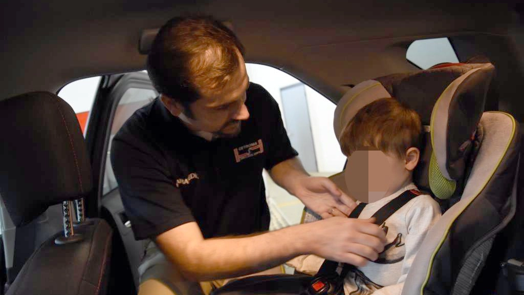 Un bambino viene assicurato sul seggiolino in auto