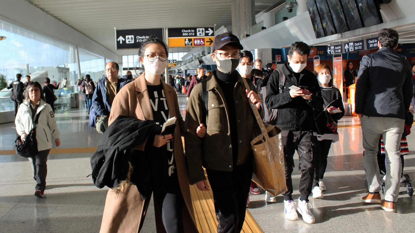 Passeggero asiatici indossano mascherine all'aeroporto di Fiumicino (Ansa)