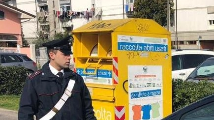 I carabinieri davanti alla campana gialla che raccoglie i vestiti usati donati dai cittadini alla Caritas