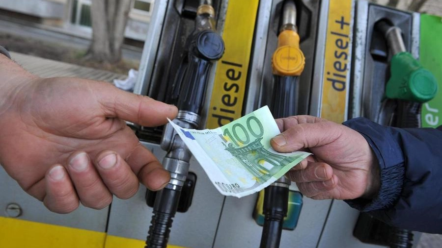 Un benzinaio alla pompa di benzina riceve il pagamento da un cliente (Ansa)