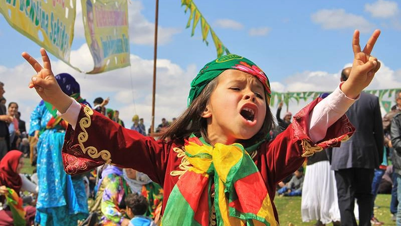 Una bimba curda festeggia il Newroz avvolta nei suoi colori