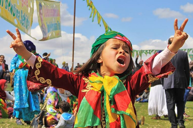Una bimba curda festeggia il Newroz avvolta nei suoi colori