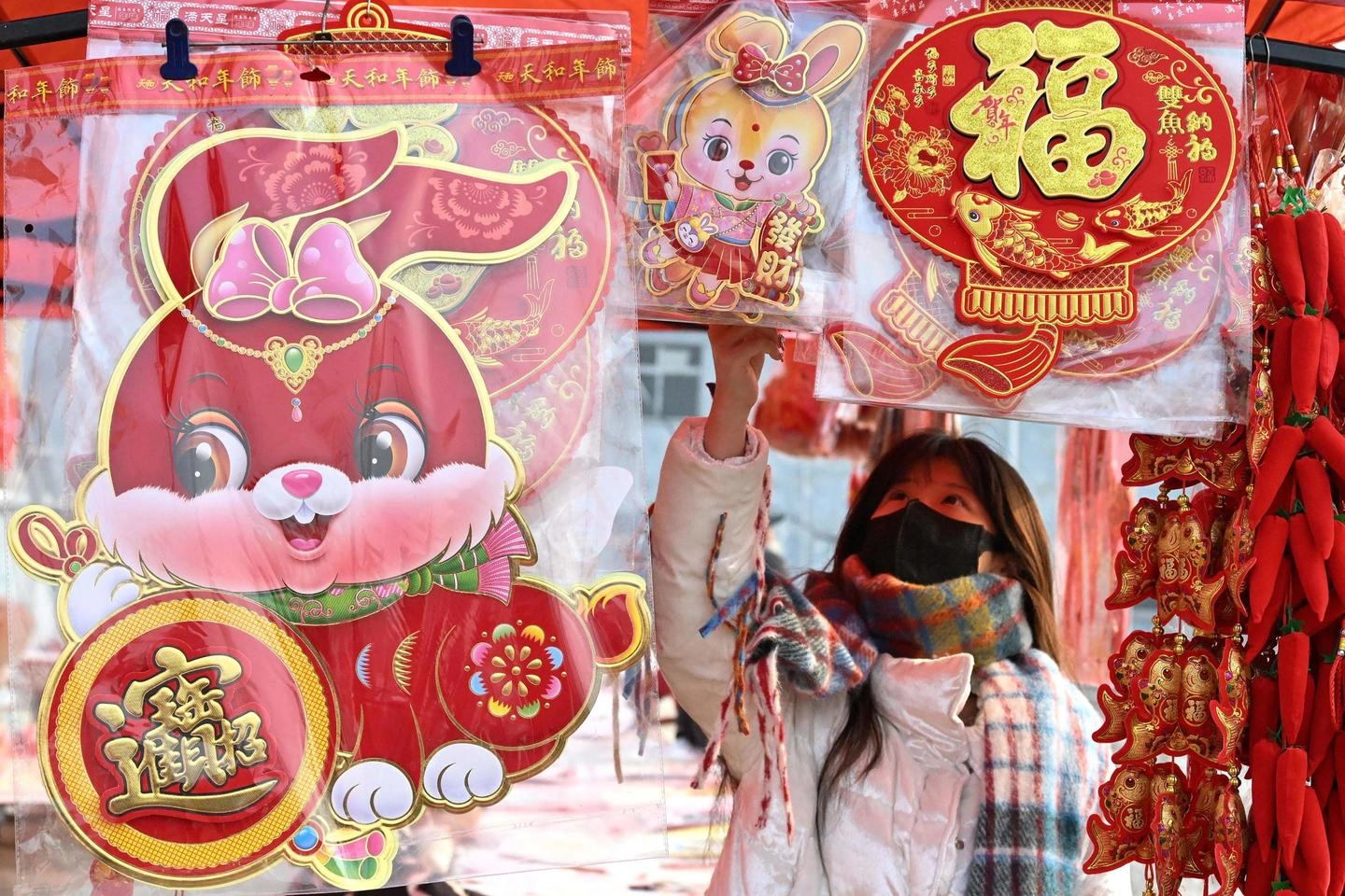 Una donna in un mercato pieno di decorazioni per il Capodanno lunare cinese (Afp)