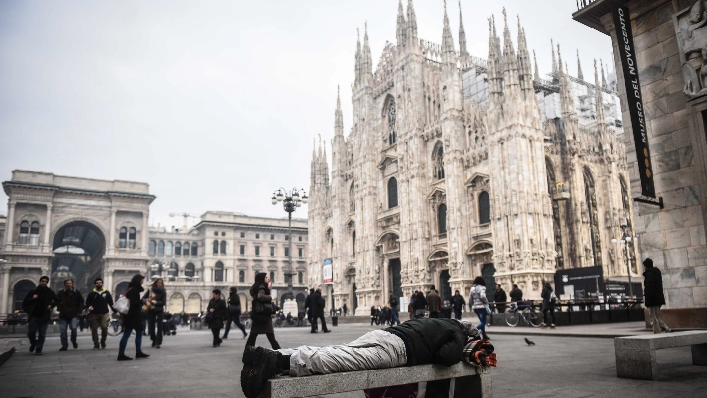 Un senzatetto su una panchina in piazza Duomo 