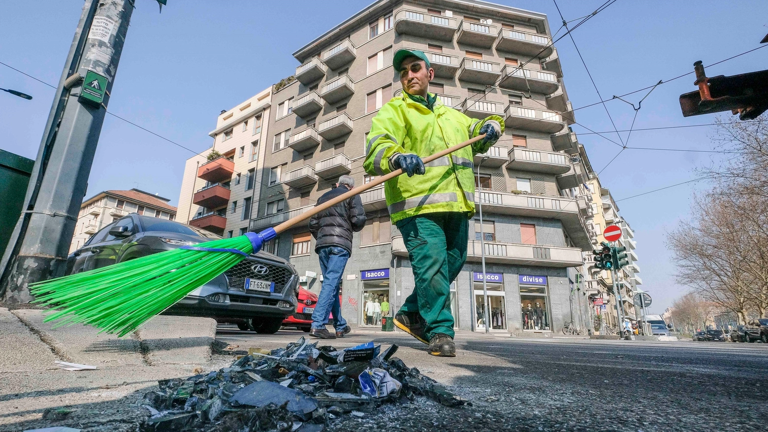 Un operatore Amsa racoglie i rifiuti abbandonati sul marciapiede (NewPress)