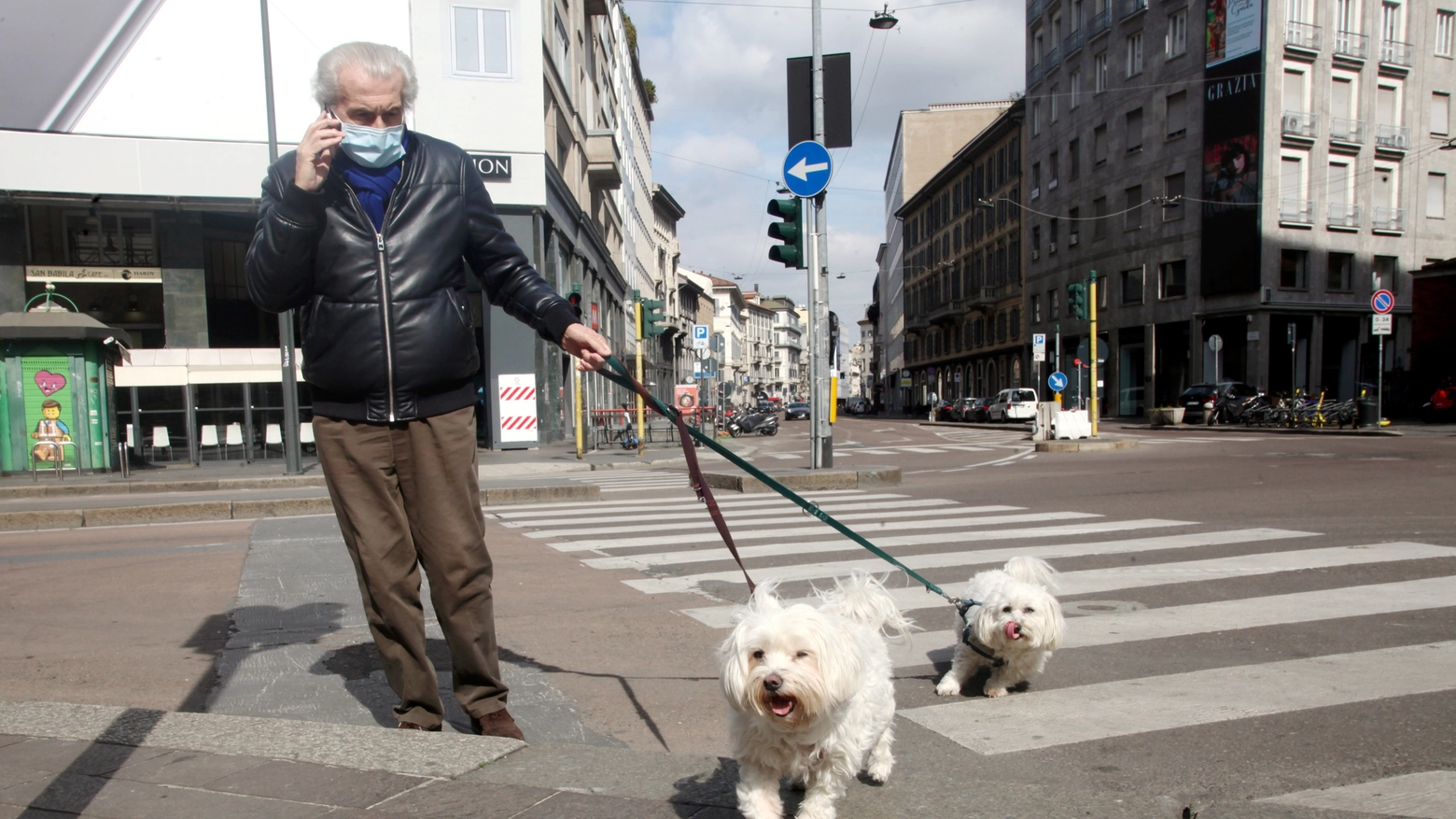 Una persona in mascherina porta a spasso i cani 