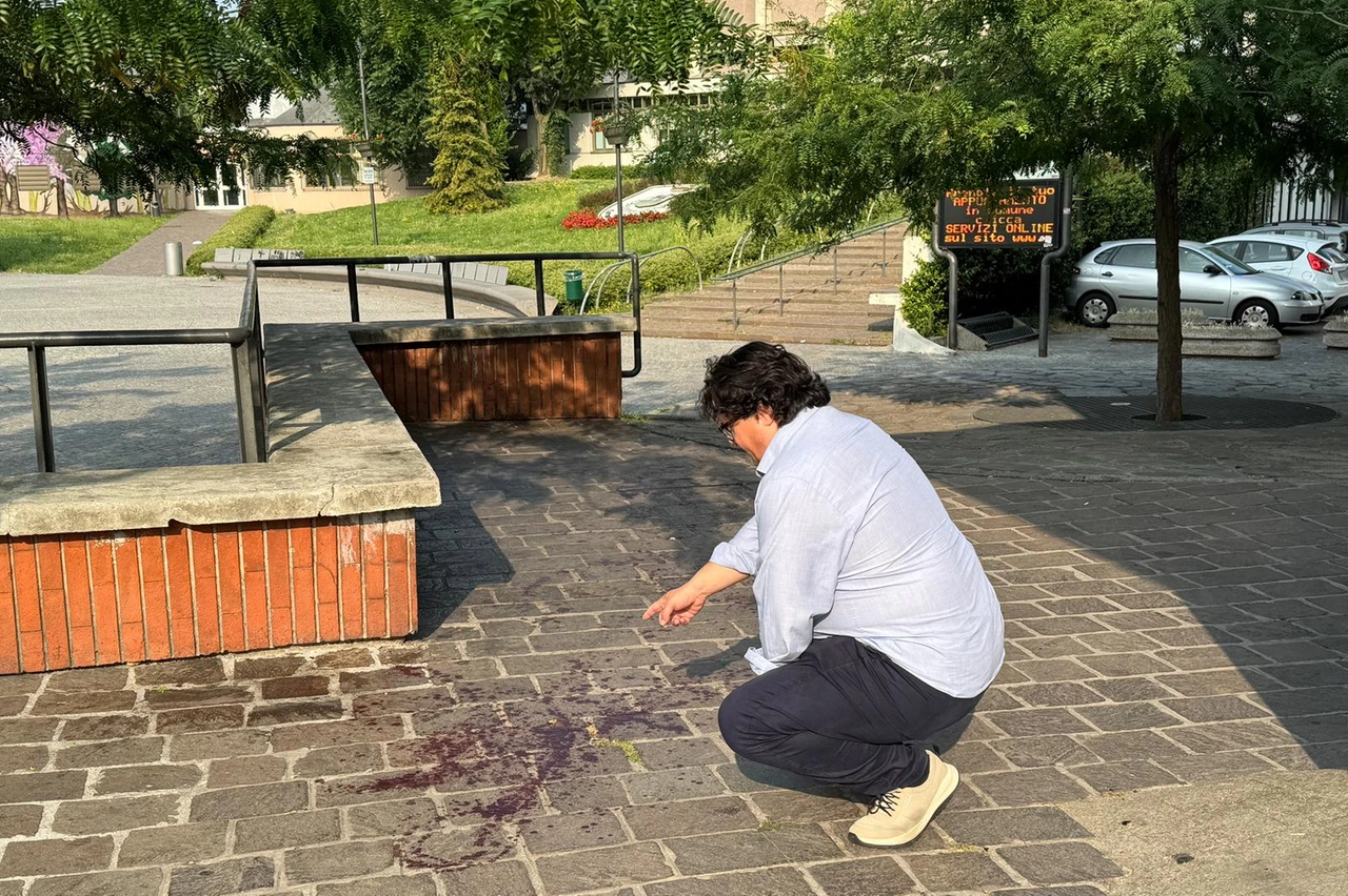 La macchia di sangue sul pavè di piazza Foglia a Rozzano dove due uomini sono stati raggiunti da colpi di arma da fuoco (Mdf)